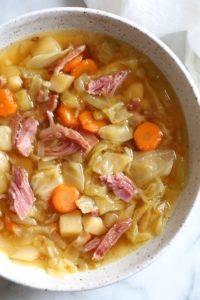 A bowl of ham bone soup with potatoes and cabbage